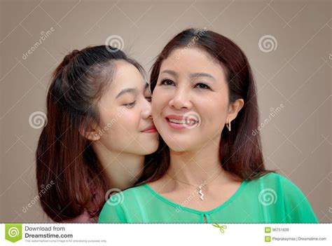 asian girl hugging and kissing her mother mother day stock