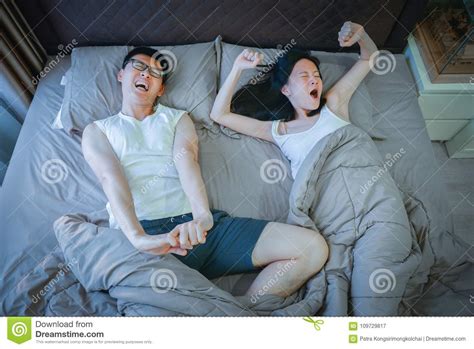 Asian Couple Stretching On Bed In Bedroom Stock Image