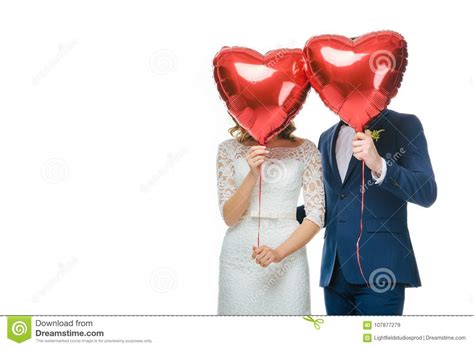 Wedding Couple Covering Faces With Red Heart Shaped Balloons Stock