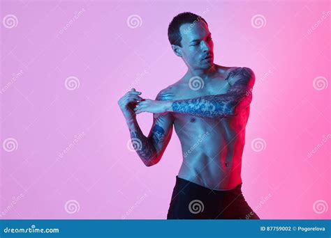 muscular sport man naked torso making arm stretch on a color background