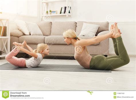 mother and daughter doing yoga exercises at home stock