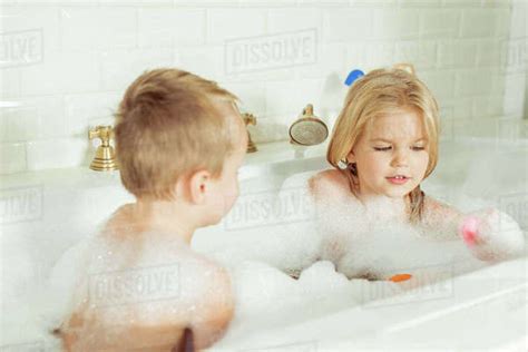 adorable little brother and sister playing together in bathtub with