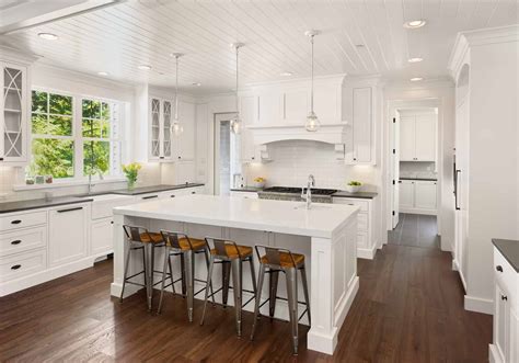 beautiful white kitchen   luxury home  island pendant lights  hardwood floors
