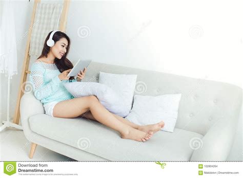 asian woman enjoying sitting on couch and listening to music stock