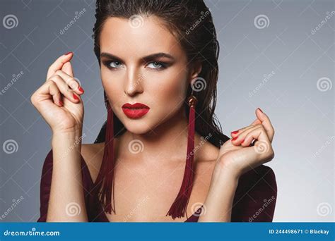 stunning woman with a beautiful makeup wearing long red earrings stock