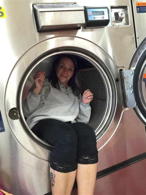 women sitting inside a front load washing machine 24 hour laundromat
