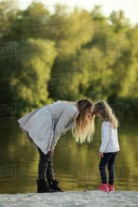 Mother Walks Together With Her Daughter On Beach Near River Stock