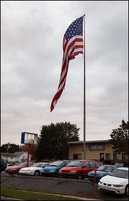 Used car dealer with a huge American flag | Photograph by