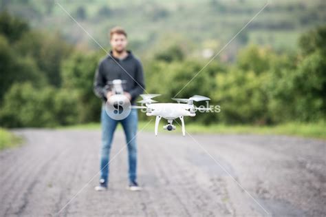 young hipster man  remote control  flying drone  camera green sunny nature royalty