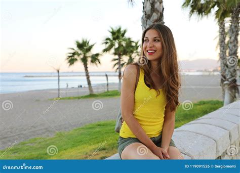 Happy Beautiful Woman Sitting And Looking The Beach At Sunset In Her