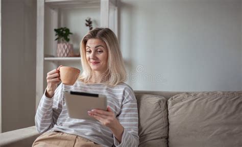 jeune femme surprise utilisant une tablette assise sur le canapé à la