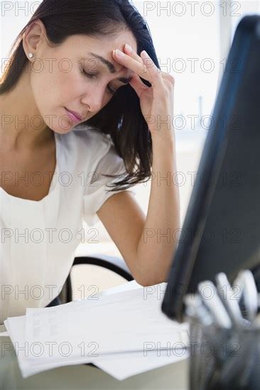 Caucasian Businesswoman Rubbing Forehead At Desk Photo12 Tetra Images