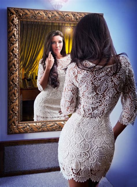 the beautiful girl in a short white dress looking into mirror stock