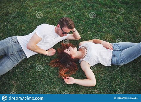ein romantisches paar von den jungen leuten die auf dem gras im park liegen beschneidungspfad