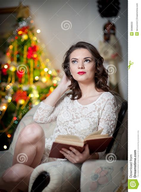 Beautiful Woman With Xmas Tree In Background Reading A Book Sitting On