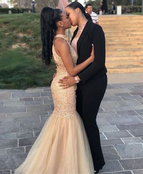 Two Women In Formal Wear Kissing Each Other On The Cheek While Standing