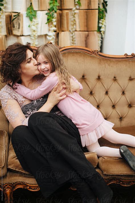 Mother And Daughter Cuddling And Kissing Each Other Indoors By