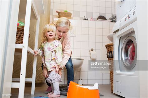Girl Assisting Sister To Wear Pants At Bathroom Photo Getty Images