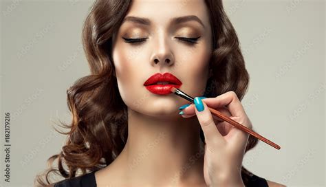 makeup artist applies red lipstick beautiful woman face hand of make