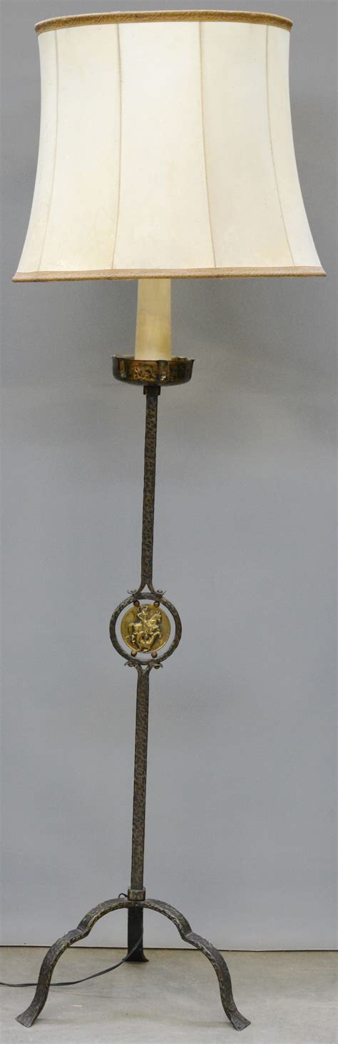 een smeedijzeren staande lamp met een messingen plaquette van sint joris jordaens nv