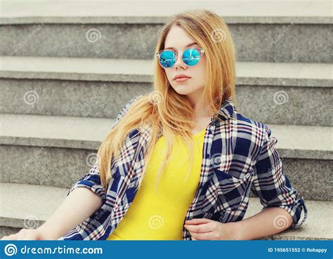 portrait of blonde teenager girl wearing sunglasses looking at camera