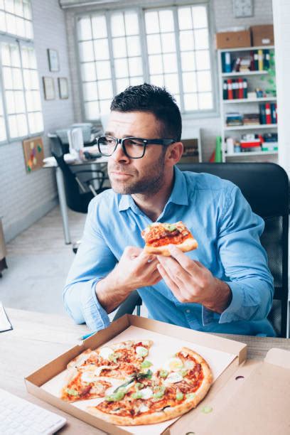 20 hombre de negocios cansado de comer pizza en la oficina fotografías