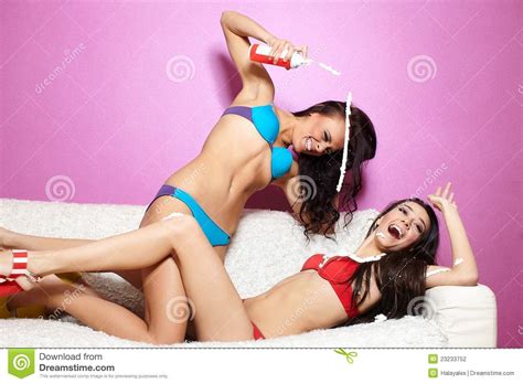 two girls pplying cream milk on white sofa stock