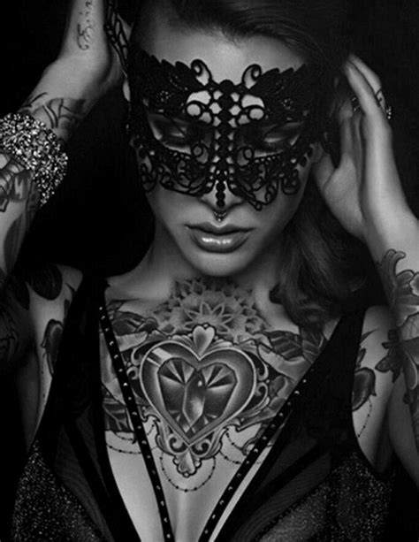 A Woman Wearing A Black Mask With Tattoos On Her Arm And Hands Behind