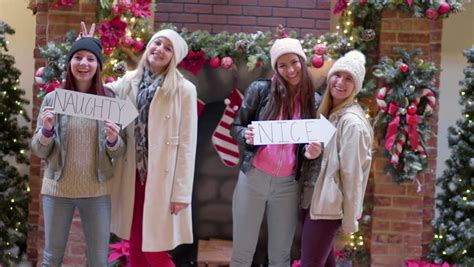 group of fun teens pose with naughty and nice signs at mall for christmas pictures naughty