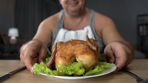 glimlachend zwaarlijvig mannetje die vettige geroosterde kip het te veel eten en ongezonde kost