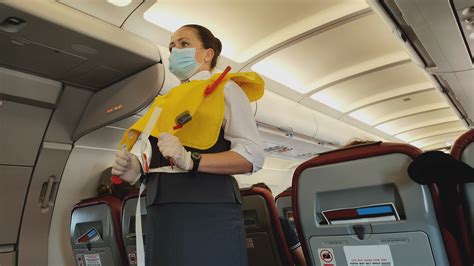 woman stewardess flight attendant  face mask presenting life vest  board   flight
