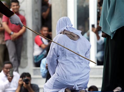 men laugh as woman caned in public for having sex outside marriage in