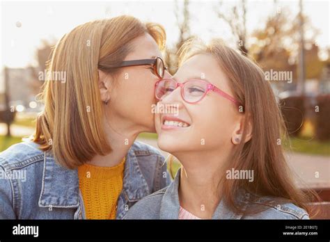 Happy Young Girl Laughing As Her Mom Kissing Her On The Cheek Cheerful