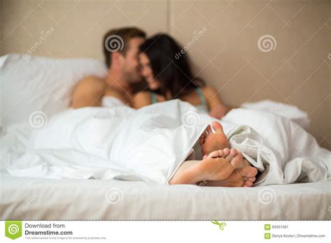 feet of a couple in bed under the blanket royalty free