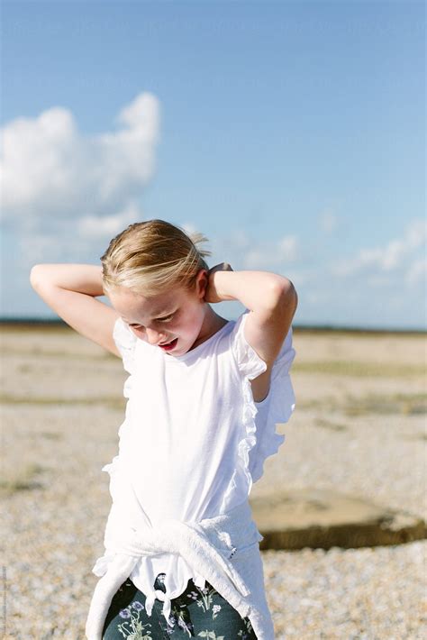 preteen girl outdoors on a shingle beach she is not looking at the
