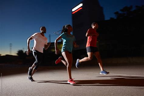 group  black athletes running  night  urban area  stocksy contributor miquel llonch