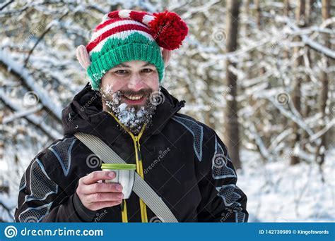 snow bearded christmas elf holding a mug of hot tea and