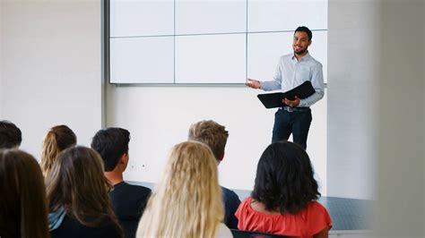 teacher giving presentation to high school class in front of screen