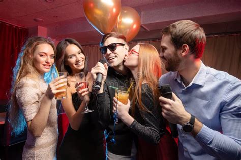 Group Of Young People Singing Into Microphone In Karaoke Bar Stock