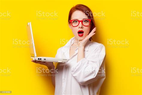 surprised redhead girl in oversized white shirt holding a pc stock