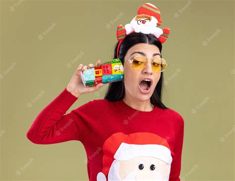 Jovem Curiosa Caucasiana Usando Bandana De Papai Noel E Suéter Com