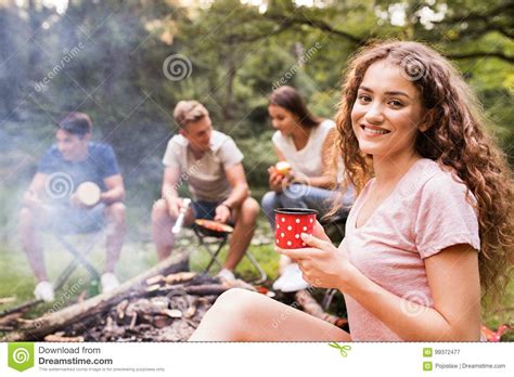 teenagers camping cooking meat on bonfire stock image
