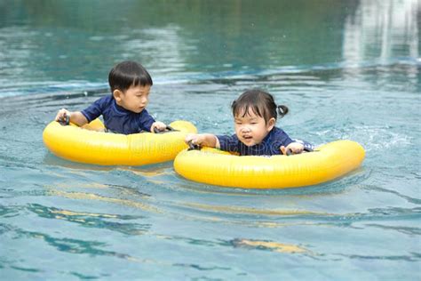 Brother And Sister Playing With Inflatable Boat In The Swimming Pool