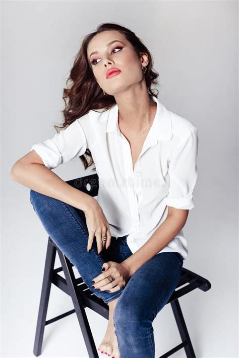 fashion model sitting   chair   blouse  jeans barefoot stock