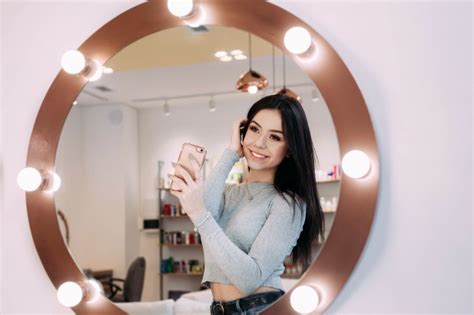woman makes selfie in makeup mirror with lamps photo free download