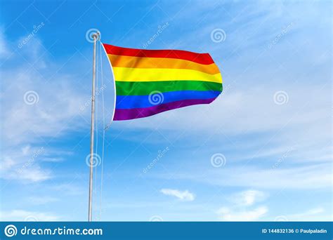 rainbow pride gay lgbt flag over blue sky background stock