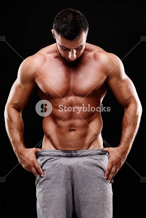 Muscular Man In White Pants Posing Confidently On Black Background