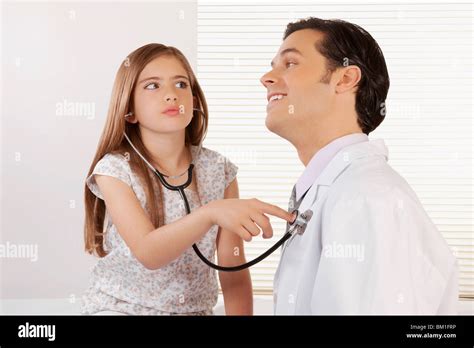 girl listening to the heartbeat of a doctor with a stethoscope stock