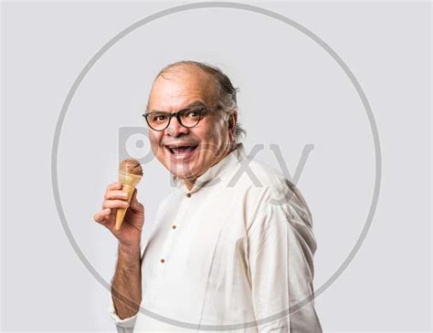 Image Of Retired Indian Old Man Eating Ice Cream Standing Icolated