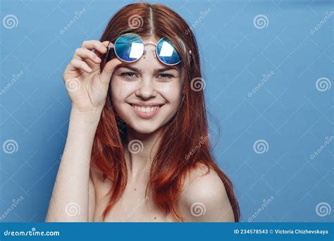 perky red haired woman in blue glasses bare shoulders posing stock